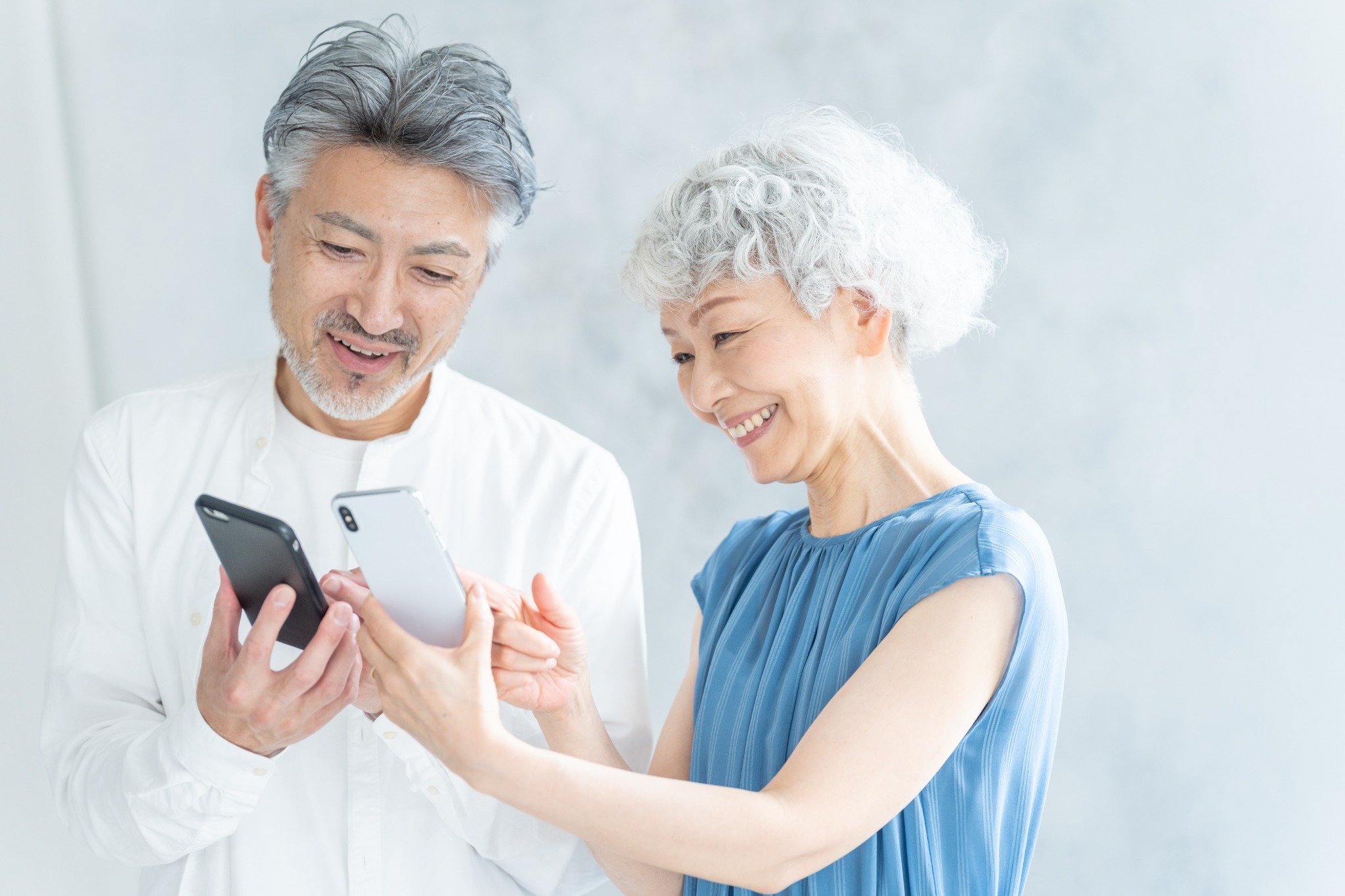 スマートフォンを見ながら笑顔で相談するシニア夫婦